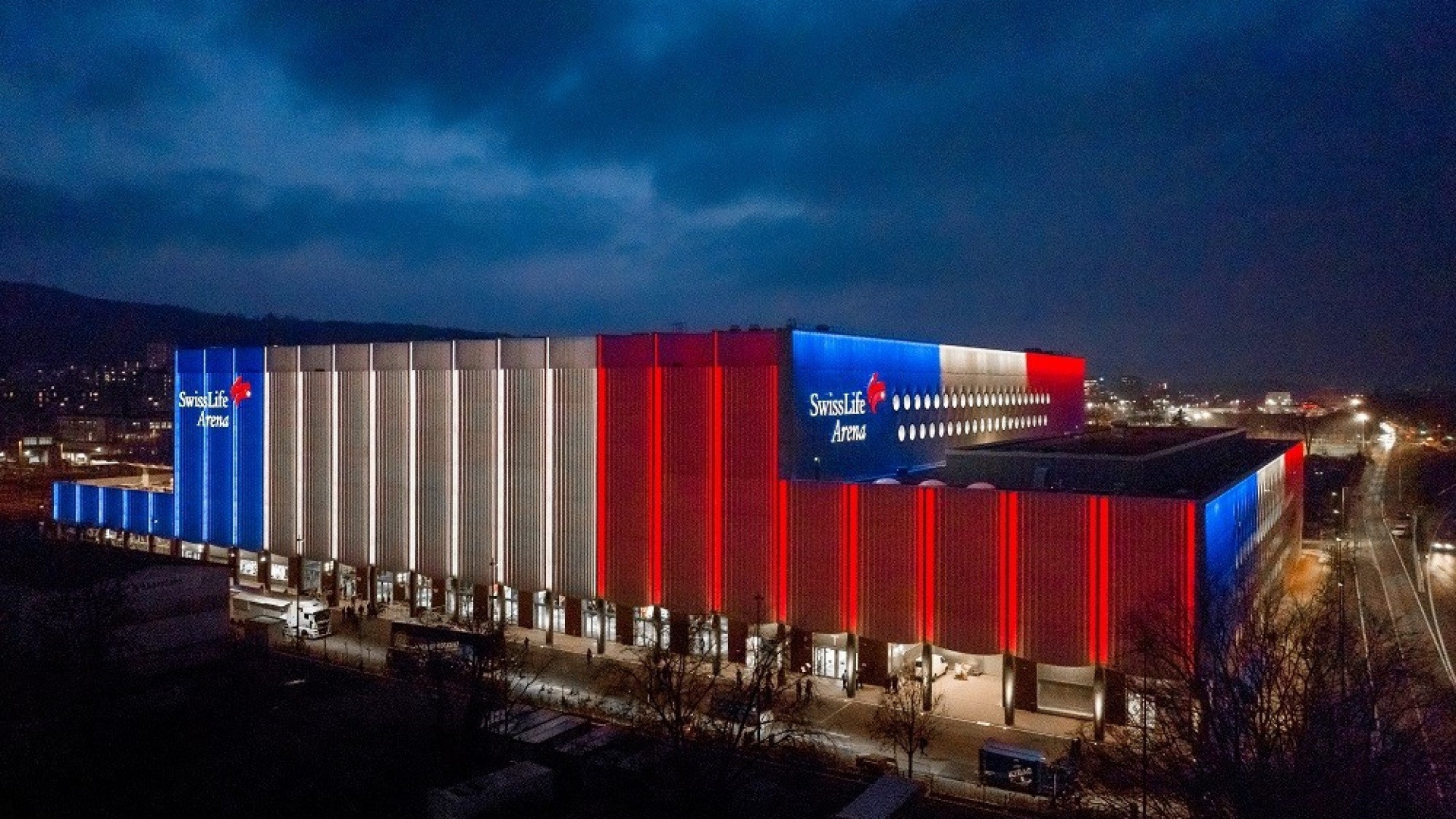 Swiss Life Arena Zürich-Altstetten bei Nacht mit blau-roter Fassadenbeleuchtung